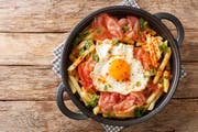 Huevos Rotos with fried potatoes and hamclose-up in a plate on the table. Horizontal top view from above