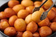 Loukoumades or luqaimat or lokma in black bowl. Loukoumades is an eastern cuisine donunts popular during Ramazan. Popular Ramadan Food. Iftar and Suhur sweets. Close up